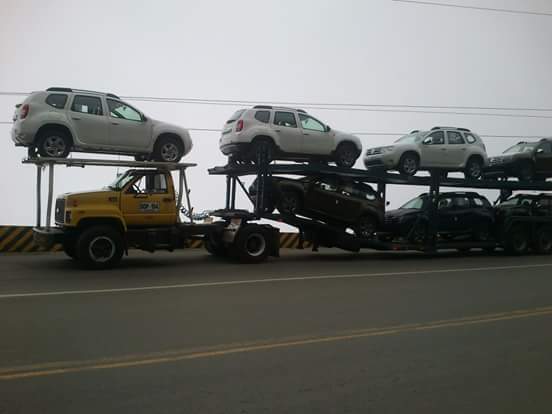 Camionetas cargadas en niñera sobre la vía